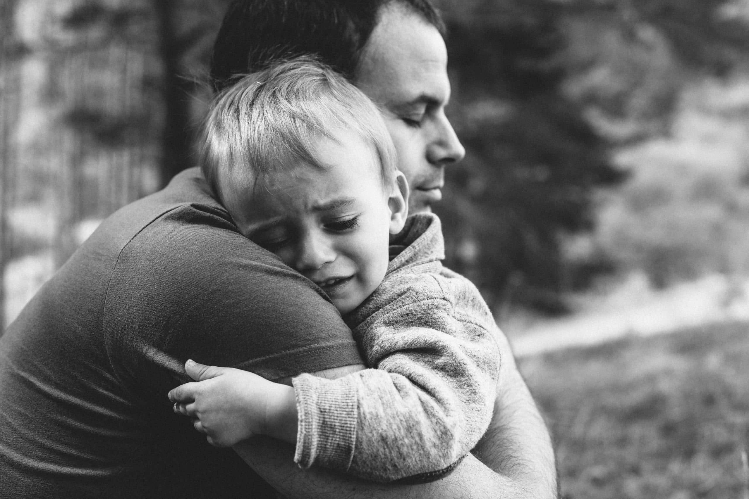 Little boy crying on father's shoulder
